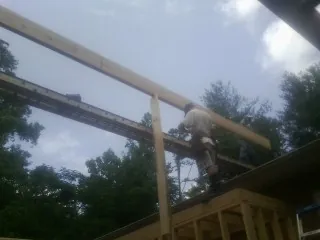 Carpenter setting a ridge beam over a new addition frame — Ice Dam Removal by Roofing Brothers in Gridley