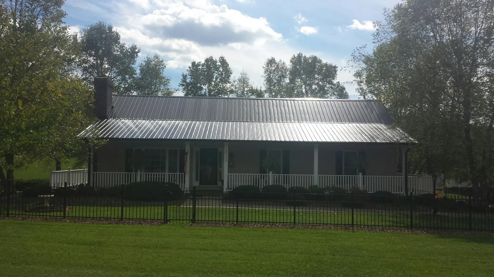 Gray metal roof on a brick ranch with a full width front porch — Gutter Guard Installation work by our crew in Gridley