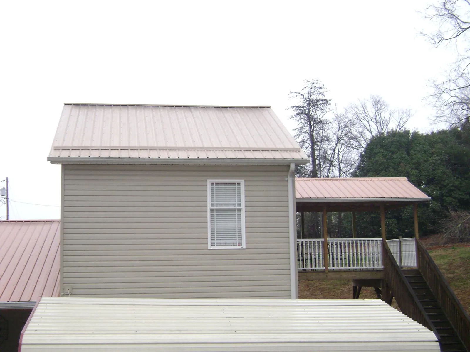 Tan metal roofs on a two story addition and attached porch, from a Roof Replacement job in Gridley