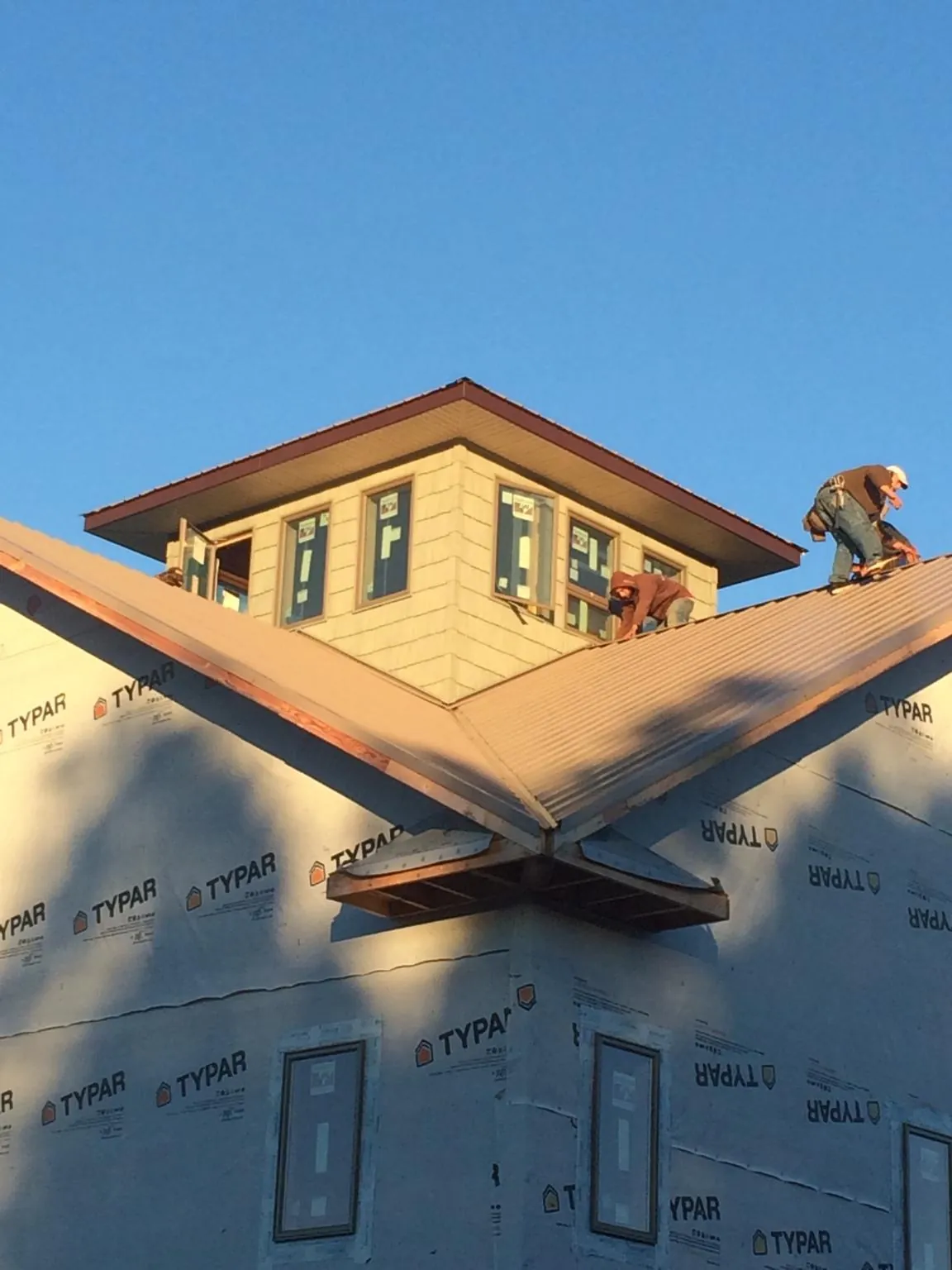 Roofers working around a rooftop cupola on a new metal roof at sunset — Roof Waterproofing in Gridley by Roofing Brothers